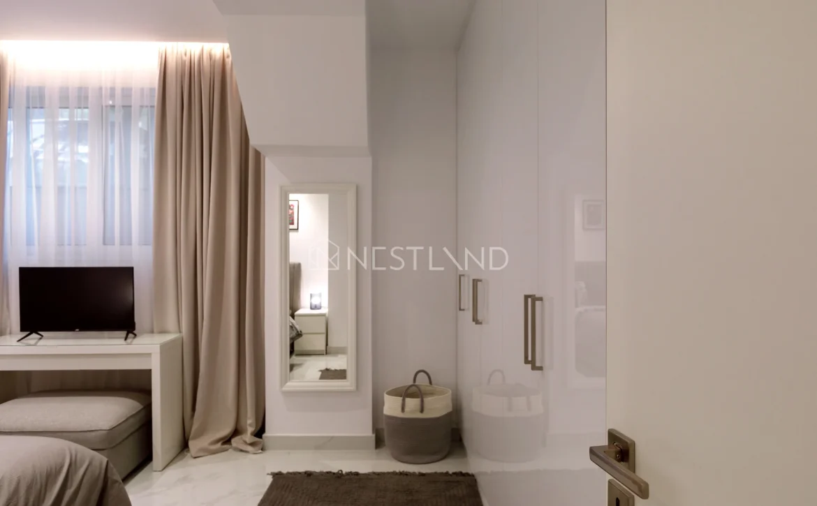 Elegant minimalistic bedroom with a TV, neutral tones, and sheer curtains.