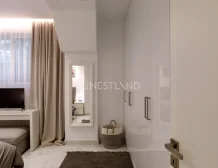 Elegant minimalistic bedroom with a TV, neutral tones, and sheer curtains.