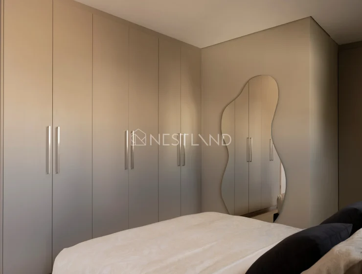 Modern bedroom with a large built-in wardrobe and an elegant mirror.