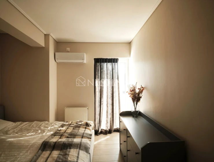 A modern bedroom with a bed, window with curtains, dresser, and an air conditioner.