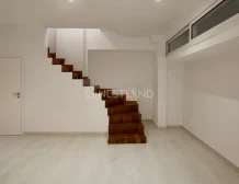Modern interior with floating wooden staircase, white walls, and marble floor.