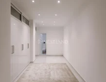 Modern hallway with white walls, built-in cabinets, and recessed lighting.