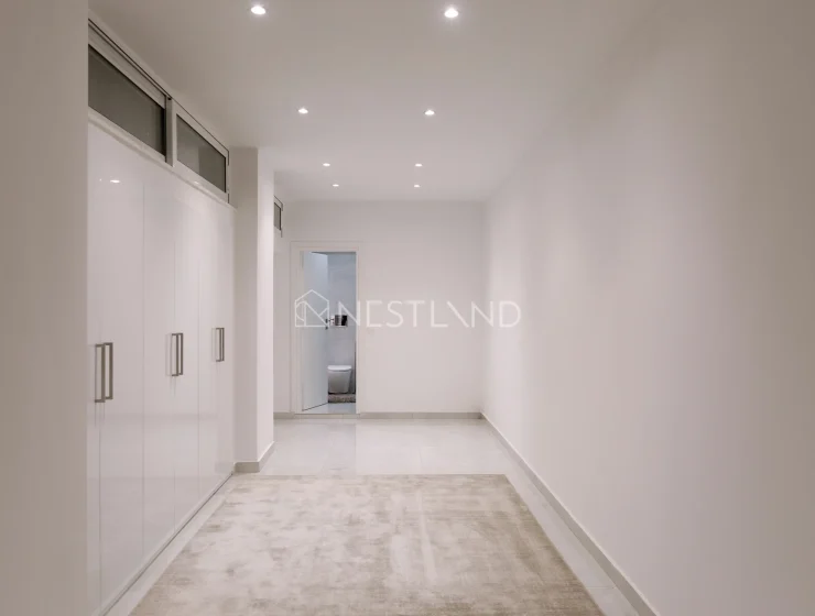 Modern hallway with white walls, built-in cabinets, and recessed lighting.