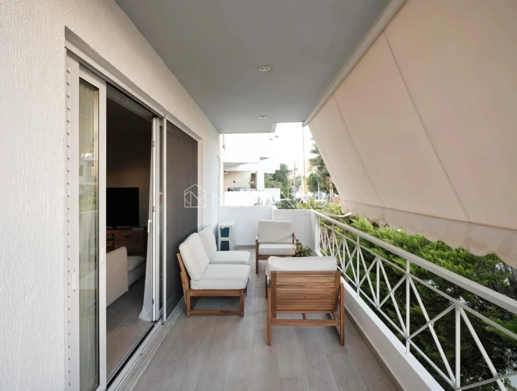 Modern balcony with outdoor furniture, plants, and an awning.