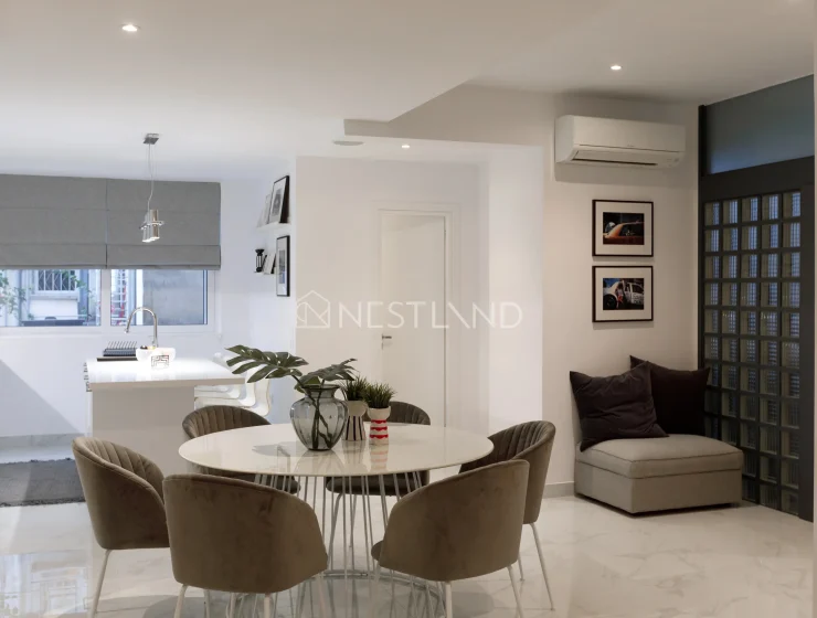 Modern kitchen and dining area with sleek design, marble flooring, and neutral tones.
