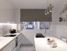 Modern kitchen interior with white cabinets, appliances, and a dining area.