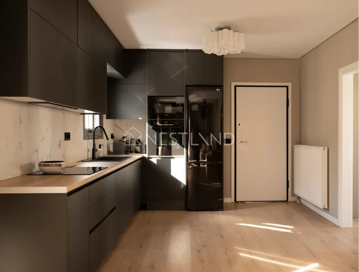 Modern kitchen interior with dark cabinetry, marble backsplash, and stainless steel appliances.