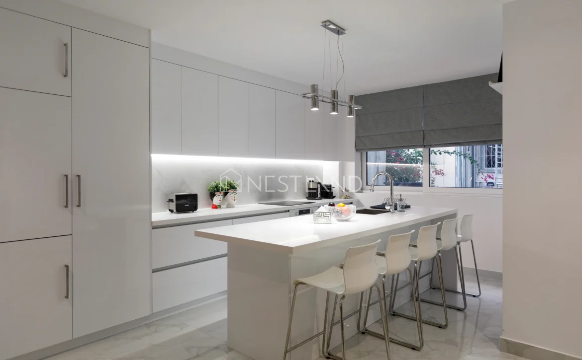 Modern kitchen interior with white cabinets, island, and pendant lights.