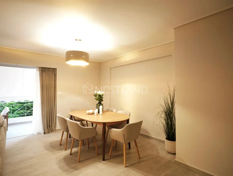 Modern dining room with wooden table, beige chairs, pendant light, and large window.