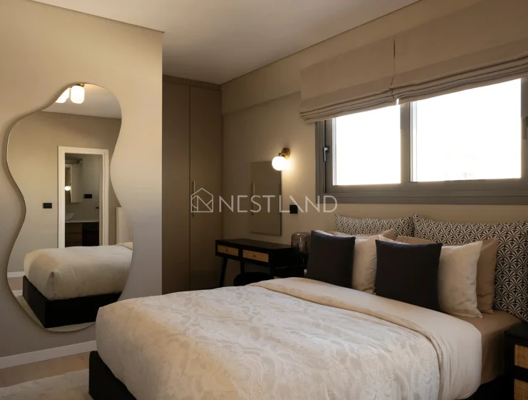 Elegant bedroom with a large bed, unique mirror, window, and stylish decor.