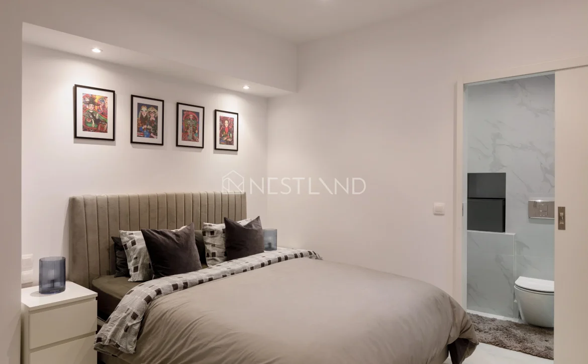 Modern bedroom with a bed, artwork on the wall, and an en suite bathroom.