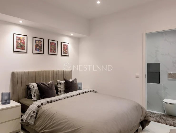 Modern bedroom with a bed, artwork on the wall, and an en suite bathroom.