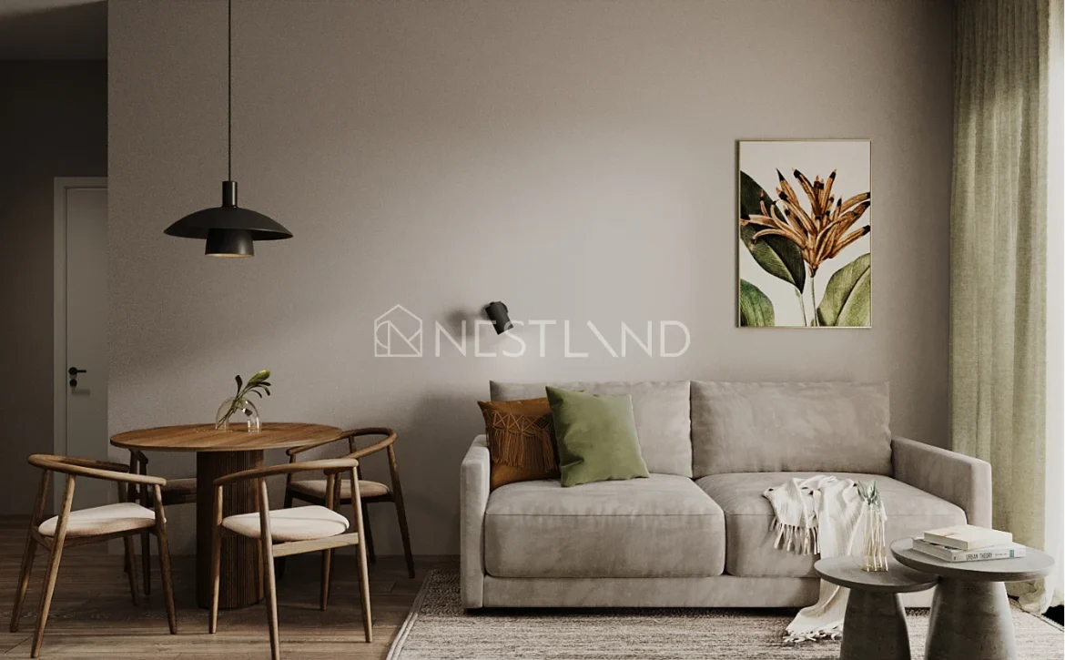 Modern living room featuring a gray sofa, round wooden dining table, stylish black pendant light, and a floral painting on soft-toned walls.