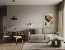 Modern living room featuring a gray sofa, round wooden dining table, stylish black pendant light, and a floral painting on soft-toned walls.