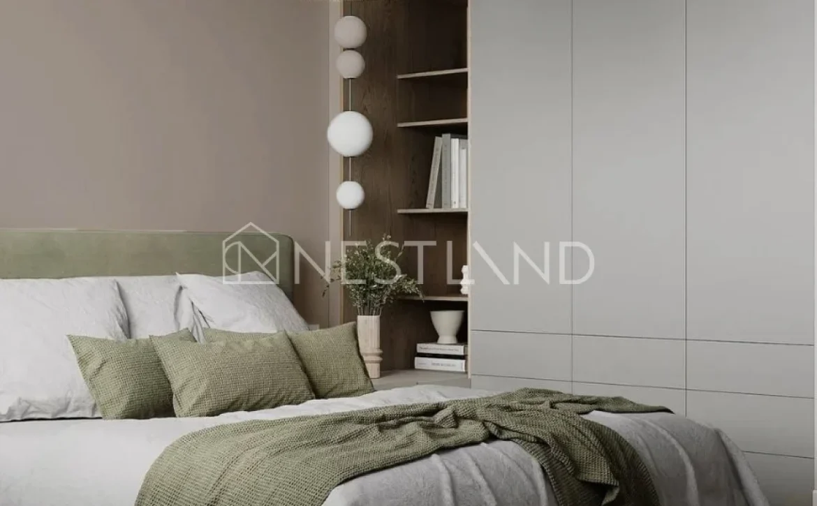 Modern bedroom featuring a cozy bed with gray and green bedding, a woven pendant lamp, and minimalist shelving against a soft beige wall.